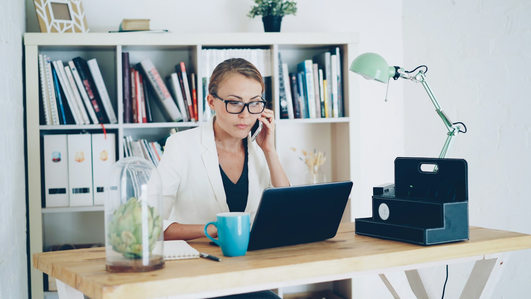 A business owner using a phone beside a laptop at a desk